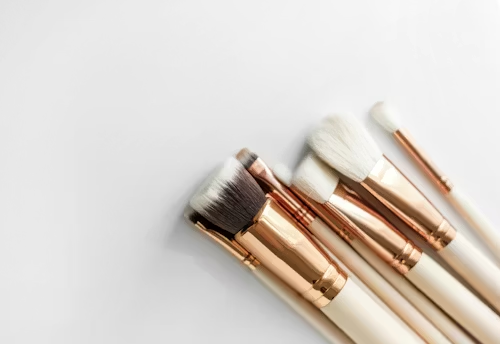 Gold and white makeup brushes on a light background